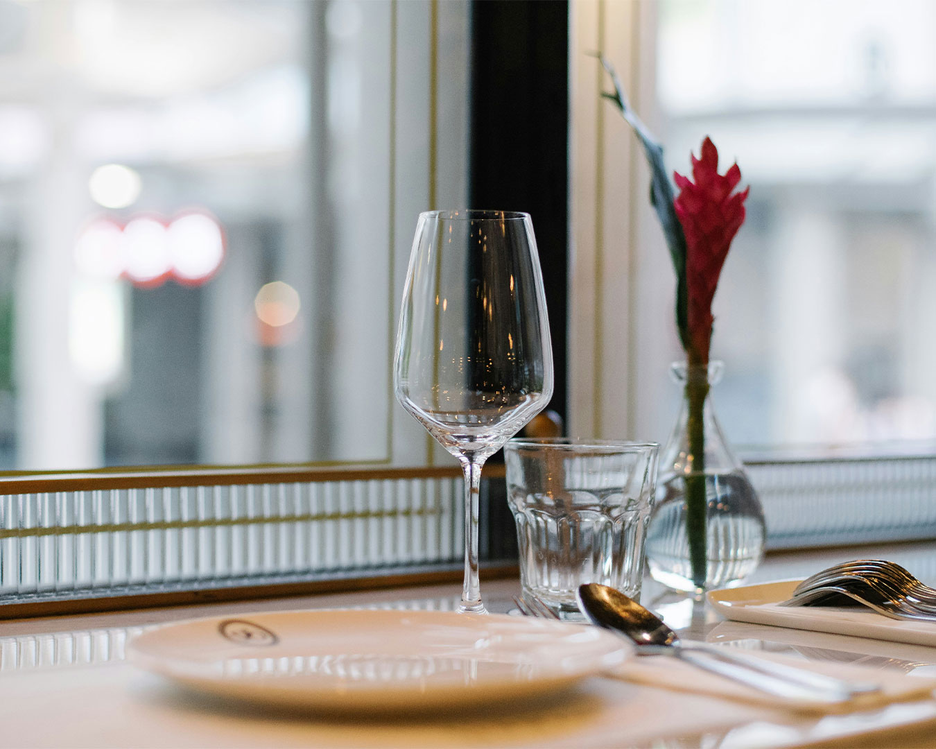 A neatly arranged glass and plate setting on a restaurant table, reflecting a clean and elegant dining atmosphere.