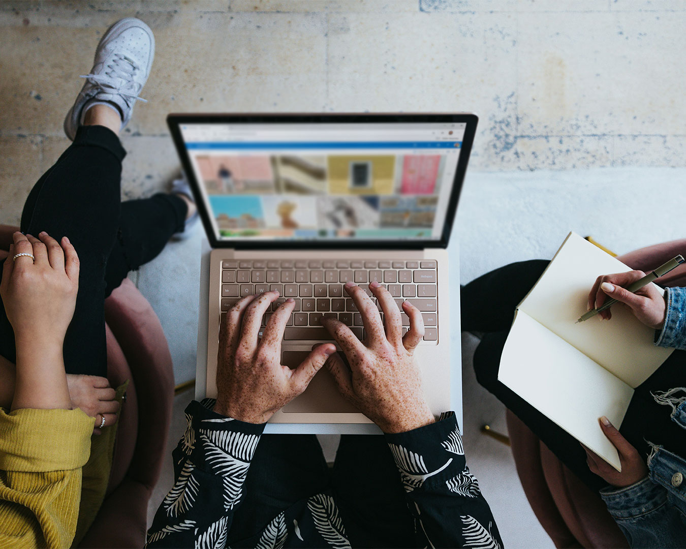 A diverse group of people seated around a table, collaborating and working on laptops, sharing ideas in a modern workspace.