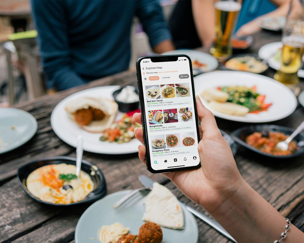 A close-up of a smartphone screen displaying a curated list of restaurants, each with ratings and photos. The interface is clear, modern, and user-friendly, suggesting someone is browsing dining options.