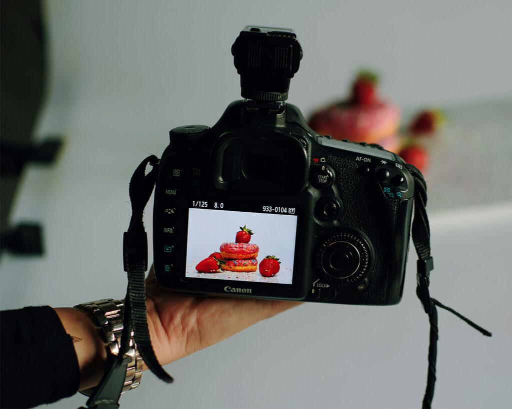 A camera capturing a strawberry donuts, representing food photography for menus, marketing, or social media content.
