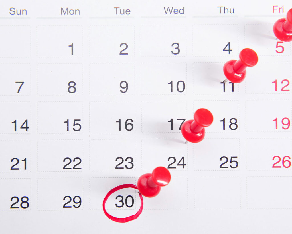 A desk calendar with a date circled in red and marked with a pin, highlighting an important upcoming event or reminder.