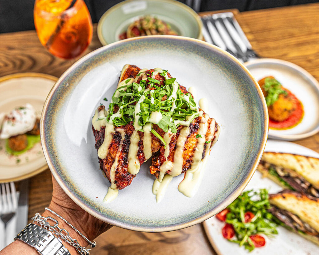 A hand holding a plate of food while taking a photo, capturing the meal for social media or personal memory.