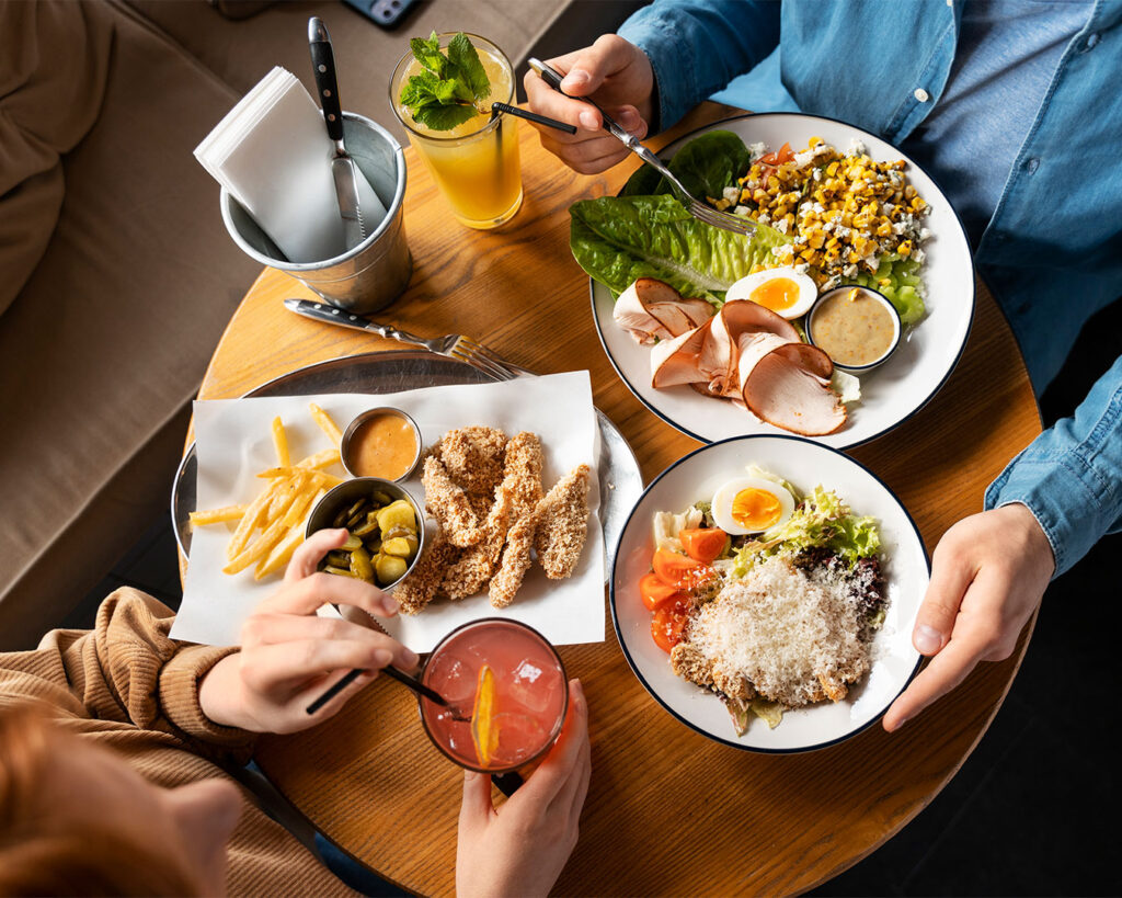 Two diners seated at a restaurant table enjoying their meal together in a relaxed and cosy setting.