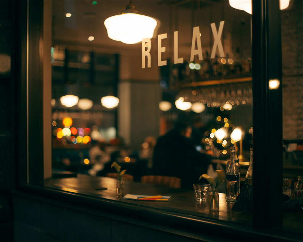 Exterior view of a cozy restaurant at night, glowing with warm lighting, creating an inviting and elegant atmosphere for diners.