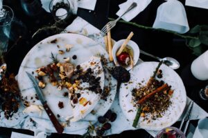 This overhead shot features an elegant, rustic spread of brie cheese, nuts, and dried fruits scattered across white marble platters.