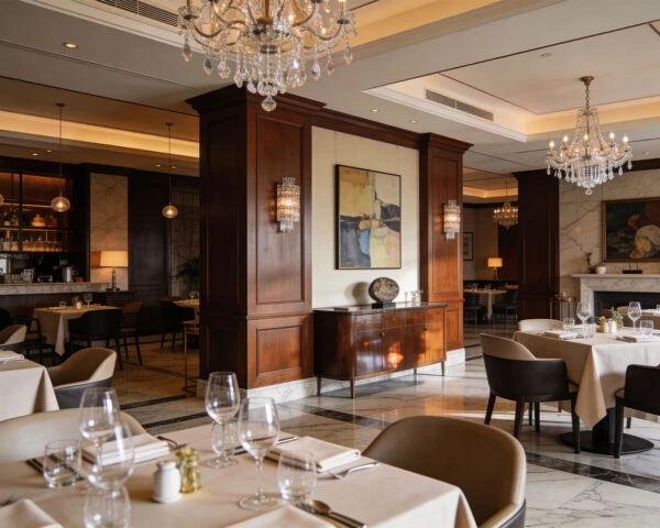 Luxurious restaurant dining room with white tablecloth settings, crystal chandeliers, marble flooring, and elegant dark wood paneling.